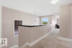 Upper-level hallway featuring neutral-toned carpeting, light gray wall paint, and white baseboards - 