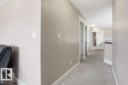 Carpeted hallway featuring warm neutral wall tones and white baseboards - 