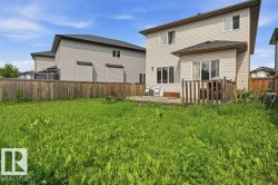 Expansive fenced backyard featuring a wooden deck, sliding glass door access, and vinyl siding - 