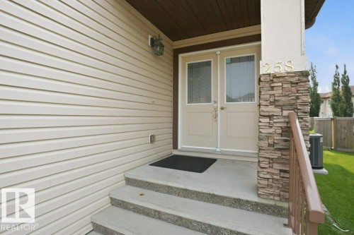 Entryway featuring double doors with decorative glass panels, stone veneer pillar, concrete steps, and a metal handrail - 258 Albany Drive Nw, Edmonton, AB - Outdoor With Exterior