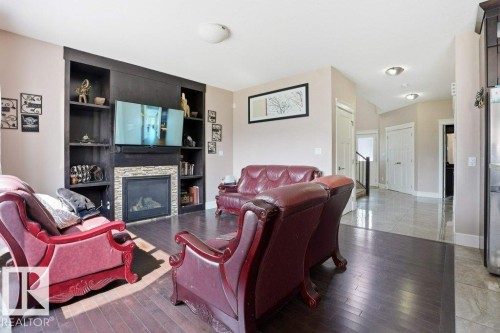 Living area with a built-in media center featuring dark wood shelving and a stone-clad fireplace - 258 Albany Drive Nw, Edmonton, AB - Indoor Photo Showing Living Room With Fireplace