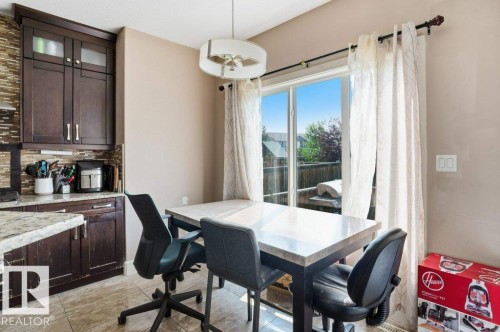Kitchen dining area featuring a sliding glass door, dark wood cabinetry, a tile backsplash, and a light fixture - 258 Albany Drive Nw, Edmonton, AB - Indoor Photo Showing Other Room