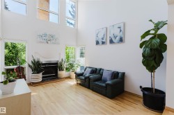 Living space featuring high ceilings, light wood-finish flooring, and a fireplace with a white mantel - 