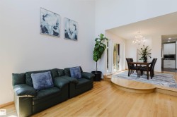 Open-concept living area featuring light wood-finish flooring, high vaulted ceilings, and white wall finishes - 