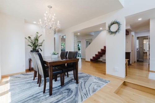 Bright dining area featuring a crystal chandelier, recessed lighting, light wood-finish flooring, and a multi-level floor plan with open archways - 342 O'Connor Close Nw, Edmonton, AB - Indoor Photo Showing Dining Room