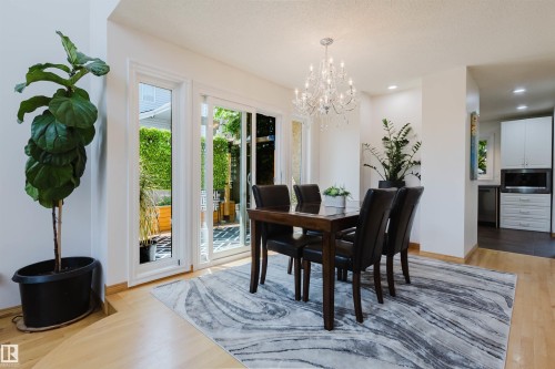 Dining area featuring wood-finish flooring, a crystal chandelier, and sliding glass doors - 342 O'Connor Close Nw, Edmonton, AB - Indoor Photo Showing Dining Room