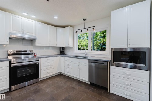 Kitchen featuring white cabinetry, stainless steel appliances, a built-in microwave, and a window above the sink - 342 O'Connor Close Nw, Edmonton, AB - Indoor Photo Showing Kitchen With Double Sink