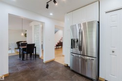 Stainless steel refrigerator with a built-in ice and water dispenser, integrated into white panel cabinetry - 