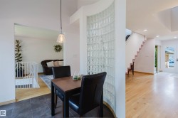 Curved glass block partition with an overhead pendant light, dark tile flooring, and light wood-finish flooring extending to a staircase - 