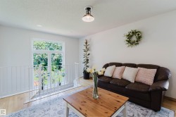 Loft area featuring light wood-finish flooring, white walls, and a white metal railing overlooking a window with exterior views - 