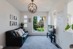 Bright living space featuring a large picture window, plush carpeting, and a contemporary spherical chandelier - 