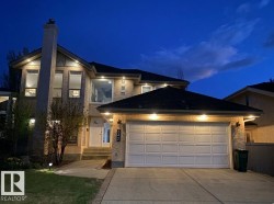 Exterior stucco residence featuring a prominent chimney, multiple large windows, and a two-car garage - 