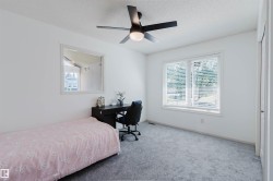 Bedroom featuring light gray carpeting, crisp white walls, a large window with white blinds, and a contemporary ceiling fan with integrated lighting - 