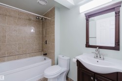 Bathroom featuring a full vanity with a dark wood-finish cabinet, integrated white sink, and a framed mirror - 