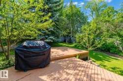 Tiered wood-finish deck with ample outdoor space, surrounded by mature trees and manicured lawn - 