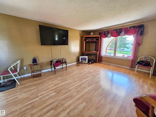 Spacious living area featuring laminate flooring, a large window - 5201 54 Street, Elk Point, AB - Indoor