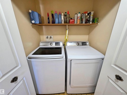 Dedicated laundry area featuring a washer and dryer, built-in shelving, and bifold doors located on the main floor - 5201 54 Street, Elk Point, AB - Indoor Photo Showing Laundry Room