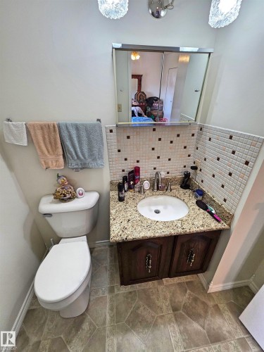 Bathroom featuring a vanity with a granite-finish countertop, undermount sink, and wood-finish cabinetry - 5201 54 Street, Elk Point, AB - Indoor Photo Showing Bathroom