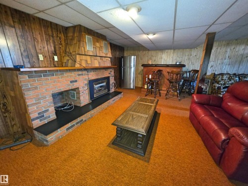 Brick gas fireplace with a dark hearth - 5201 54 Street, Elk Point, AB - Indoor Photo Showing Other Room With Fireplace