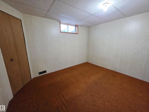 Room with wood-look paneling, dropped ceiling, and a single window - 5201 54 Street, Elk Point, AB - Indoor Photo Showing Other Room