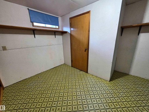 Interior space featuring patterned vinyl flooring, a wooden door, and built-in shelving - 5201 54 Street, Elk Point, AB - Indoor