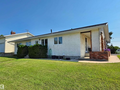 Ranch-style exterior featuring a stucco facade and a partial stone accent wall with brick details - 5201 54 Street, Elk Point, AB - Outdoor