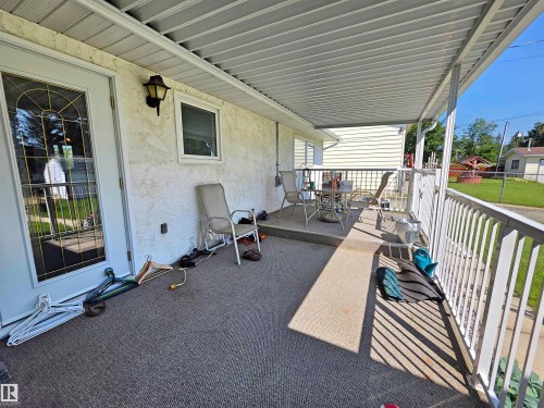 Covered patio featuring a solid roof structure and white railing - 5201 54 Street, Elk Point, AB - Outdoor With Deck Patio Veranda With Exterior