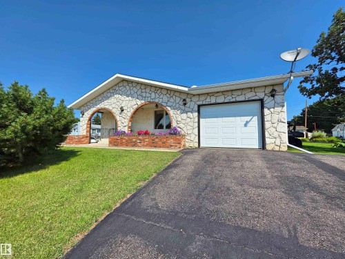Stone-clad exterior featuring a prominent arched entry porch with brick detailing - 5201 54 Street, Elk Point, AB - Outdoor