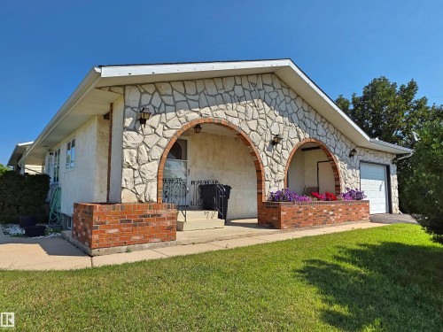 Stone facade home featuring two arched entryways with exterior lighting - 5201 54 Street, Elk Point, AB - Outdoor