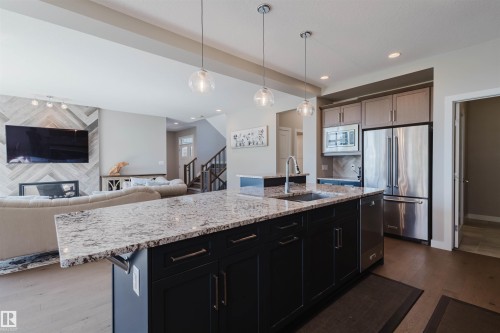 Kitchen island featuring a granite countertop, undermount sink with a gooseneck faucet, and pendant lighting - 4125 Kennedy Green Sw, Edmonton, AB - Indoor Photo Showing Kitchen With Upgraded Kitchen