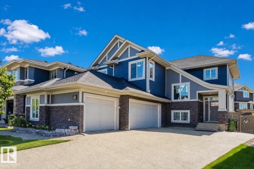 Contemporary facade featuring blue siding, stone accents, multiple gables, and an attached two-car garage - 4125 Kennedy Green Sw, Edmonton, AB - Outdoor With Facade