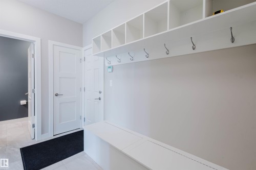 Entryway featuring a built-in white bench, overhead cubby storage, and coat hooks - 4125 Kennedy Green Sw, Edmonton, AB - Indoor Photo Showing Other Room
