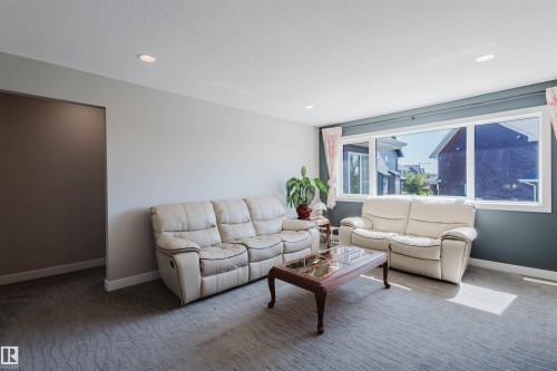 Spacious living area featuring a large picture window, recessed lighting, neutral wall tones, and textured carpeting - 4125 Kennedy Green Sw, Edmonton, AB - Indoor Photo Showing Living Room
