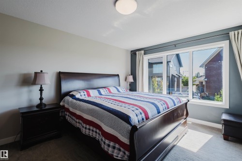 Windowed room featuring light gray and dark gray wall finishes, a large three-panel window, and light-colored carpeting - 4125 Kennedy Green Sw, Edmonton, AB - Indoor Photo Showing Bedroom