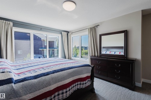 Room with broad windows, light gray walls, and textured carpet flooring - 4125 Kennedy Green Sw, Edmonton, AB - Indoor Photo Showing Bedroom