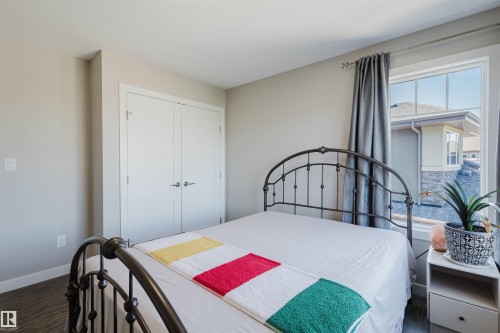 Room featuring neutral wall tones, a large window, and double closet doors with modern hardware - 4125 Kennedy Green Sw, Edmonton, AB - Indoor Photo Showing Bedroom