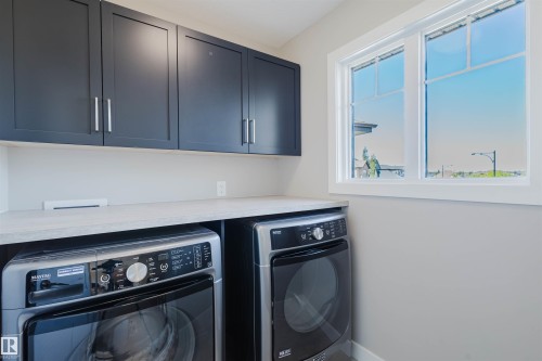 Laundry area featuring modern dark cabinetry, light-toned countertop, and bright window - 4125 Kennedy Green Sw, Edmonton, AB - Indoor Photo Showing Laundry Room