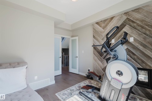 Accent wall featuring a herringbone wood-finish pattern and integrated hearth - 4125 Kennedy Green Sw, Edmonton, AB - Indoor Photo Showing Other Room