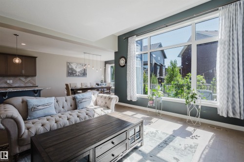 Living area featuring a large picture window with multiple panes, providing natural illumination - 4125 Kennedy Green Sw, Edmonton, AB - Indoor Photo Showing Living Room