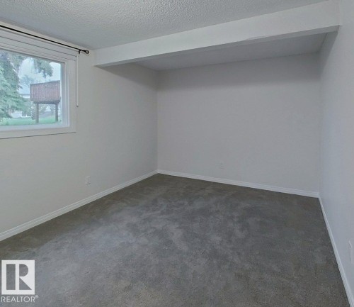 Carpeted room featuring a white-trimmed window, neutral wall paint, and white baseboards - 60 Northwoods Village Nw, Edmonton, AB - Indoor Photo Showing Other Room