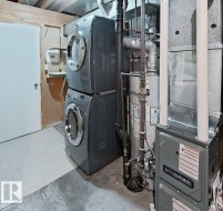 Utility area featuring a stacked washer and dryer, water heater, and furnace - 