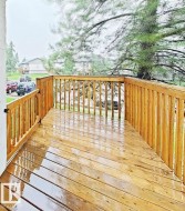 Outdoor wooden deck with natural wood railing and a visible street scene - 