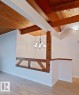 Vaulted wood-plank ceilings with exposed wood beams, a six-light chandelier, a decorative wood railing, and wood-finish flooring - 60 Northwoods Village Nw, Edmonton, AB  - Indoor Photo Showing Other Room 