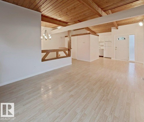 Spacious room with wood-finish flooring, exposed wood beam ceiling, white walls, and a built-in wood railing - 60 Northwoods Village Nw, Edmonton, AB - Indoor Photo Showing Other Room