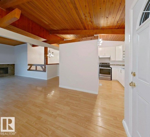 Wood-finish flooring throughout, complemented by a wood-paneled and exposed beam ceiling - 60 Northwoods Village Nw, Edmonton, AB - Indoor With Fireplace
