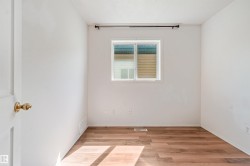 Bright interior room featuring wood-finish flooring, a white window frame, and a dark curtain rod - 