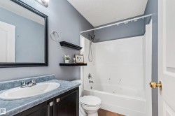 Bathroom featuring a white bathtub and shower surround, a vanity with an integrated sink, and wood-finish flooring - 