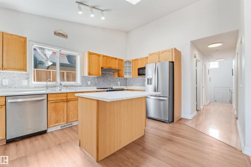 Kitchen featuring wood cabinetry, stainless steel appliances, white countertops, and a mosaic tile backsplash - 16737 116 Street Nw, Edmonton, AB 