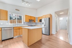 Kitchen featuring wood cabinetry, stainless steel appliances, white countertops, and a mosaic tile backsplash - 