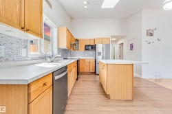 Kitchen featuring light wood cabinetry, white countertops, stainless steel appliances, and a mosaic tile backsplash - 